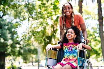 Little girl in a wheelchair at the park with her mother.