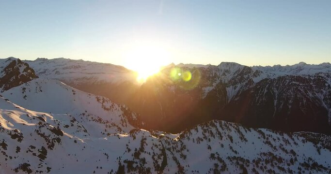 Sunrise between mountain peaks at Chamrousse, France Alps, Aerial dolly out shot