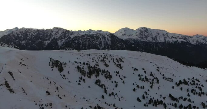 Snow capped summit of the French Alps at Chamrousse ski resort during sunrise, Aerial approach shot