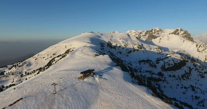 Chamrousse resort summit in the French Alps with ski lift station near sunset, Aerial flyover approach shot
