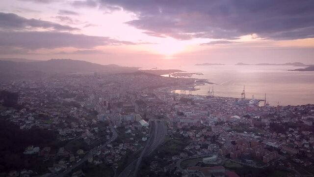 Beautiful aerial sunset view over industrial cityscape at the atlantic coast in Galicia with the Cies island in the background. Drone Stablishing shot in Vigo city.
