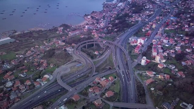 Aerial view of a small highway flyover in Galicia with the atlantic coast and a smal village. Stablishing shot Vigo city.