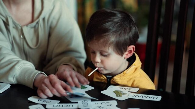 little boy learns words from cards under the ABA therapy program at home at the table