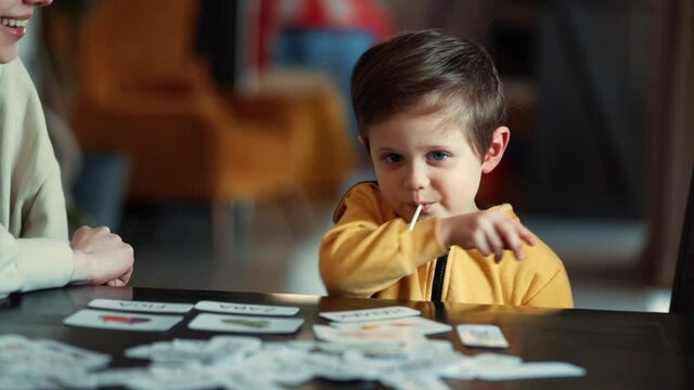 little boy learns words from cards under the ABA therapy program at home at the table