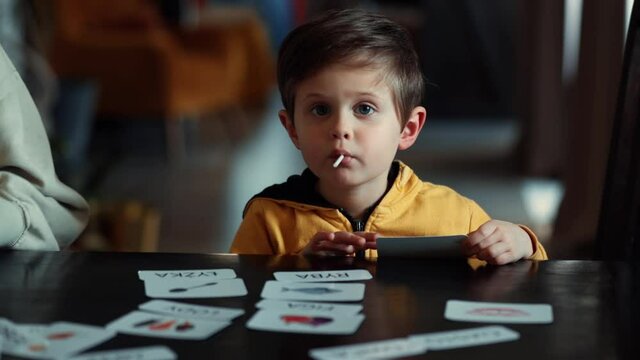 little boy learns words from cards under the ABA therapy program at home at the table