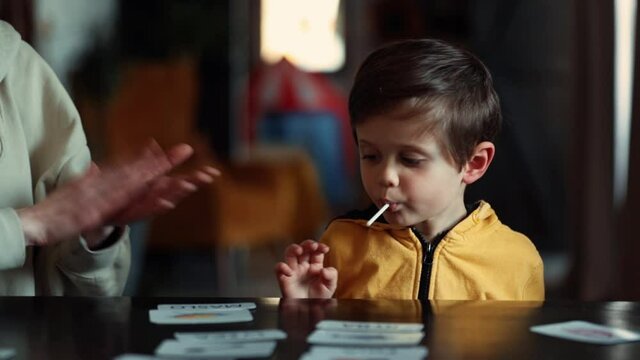 little boy learns words from cards under the ABA therapy program at home at the table