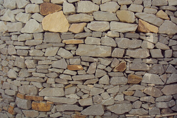 Background of the old stone wall. Gray and brown stones of an old building with sun spots. View from above. Place for text