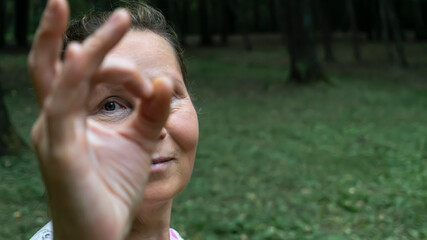 A woman shows emotion. In the background are grass and trees. Selective focus.