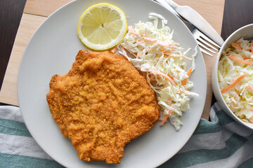 Pork Schnitzel with coleslaw and lemon on a plate. 