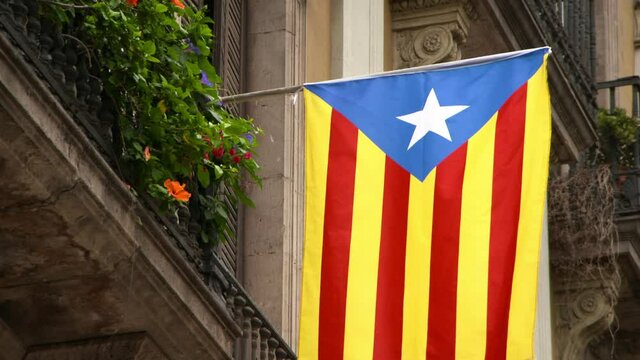 Estelada Blava Flag Waves Gently In Breeze From Decorative Limestone Fa�ade With Potted Window Flowers In The Sunshine