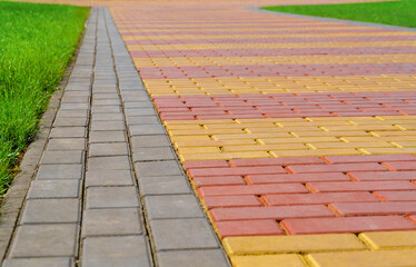 walkway made of paving slabs and green grass as a background, bright sunlight