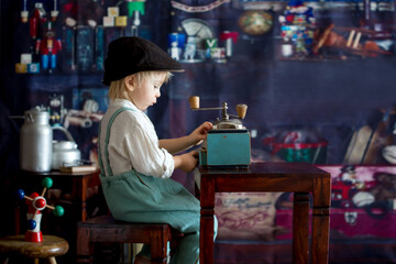 Little toddler boy, playing with mill at home, sitting on vintage table