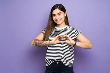Cute hispanic woman making a heart shape with her fingers