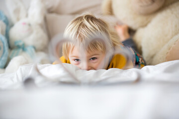 Beautiful child, toddler boy, reading book and playing with it, creative knowledge shot with book