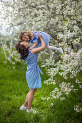 happy mom and daughter in the spring blooming garden playing together