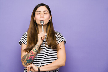 Latin woman with cravings using a spoon to eat