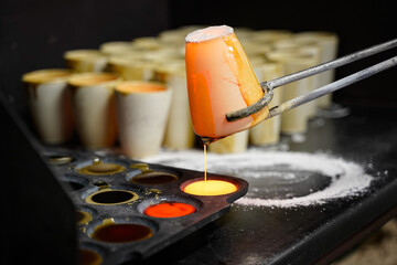 Melted rock, metal in a ceramic cup and poured into a form