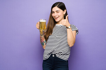 Latin woman with thumbs up and drinking a beer