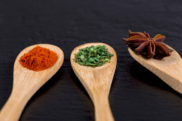 Close-up of wooden spoons with spice on black stone