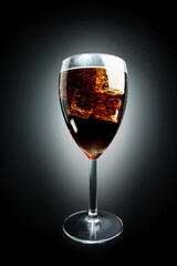 Cola in glass with ice on black background
