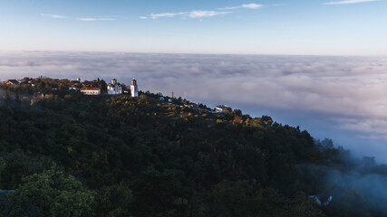 Fototapeta na wymiar View of the church on the hill above the clouds