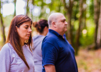 Obraz premium Wellness meditation workshop hispanic adult group relax together with eyes closed in a forest. Breathing in the calm of nature feeling the harmony, health and relieving stress 