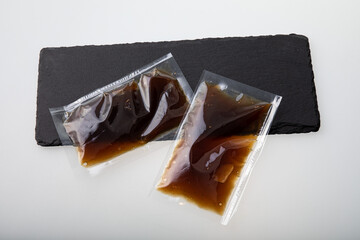 Brown sauce in vacuum sealed plastic bag on black slate board