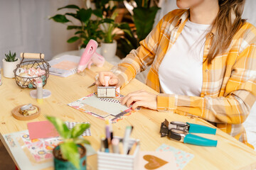 Cropped shot of women making homemade scrapbooking album from paper. DIY, hobby concept, gift idea, decor with handcraft attributes, home production, the process of creation, creativity.