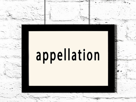 Black frame hanging on white brick wall with inscription appellation