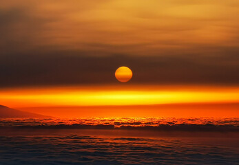 Juicy sunset in the mountains above the clouds with the sun close up during a Сalima sandstorm