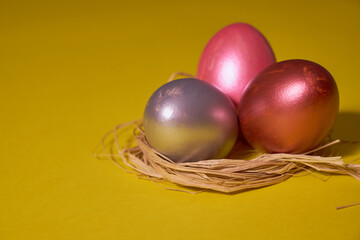 Pearl colored eggs in the nest on a yellow background.
