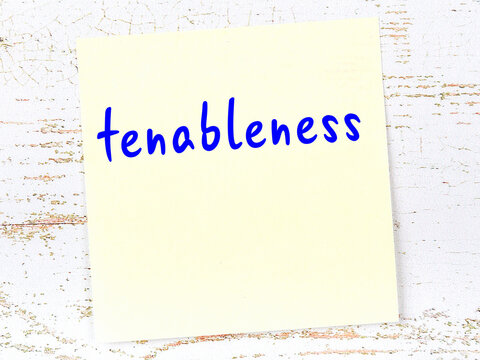 Yellow sticky note on wooden wall with handwritten word tenableness