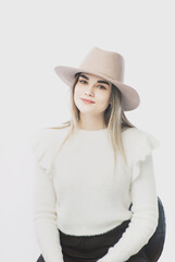 Fototapeta na wymiar girl in a white sweater posing in a felt hat on a light background