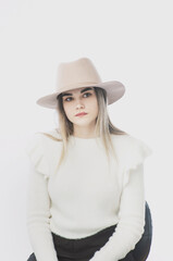 Fototapeta premium girl in a white sweater posing in a felt hat on a light background