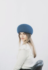 Fototapeta premium girl in a white sweater posing in a felt hat on a light background