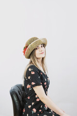 girl in a sundress and straw hat posing on a light, solid background