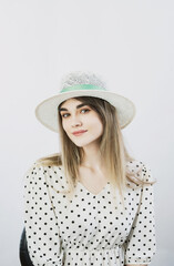 girl in a sundress and straw hat posing on a light, solid background