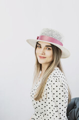 girl in a sundress and straw hat posing on a light, solid background