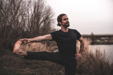 Young man stretching and relaxing on a yoga session in the park. Breathing technique, healthy,...