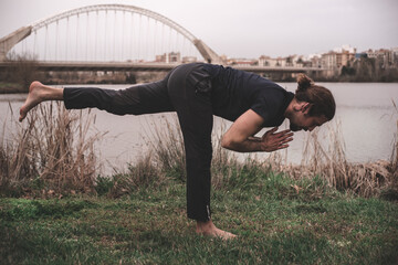 Young man stretching and relaxing on a yoga session in the park. Breathing technique, healthy,...