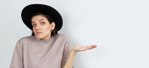 Portrait of a young woman shrugging shoulders over white background