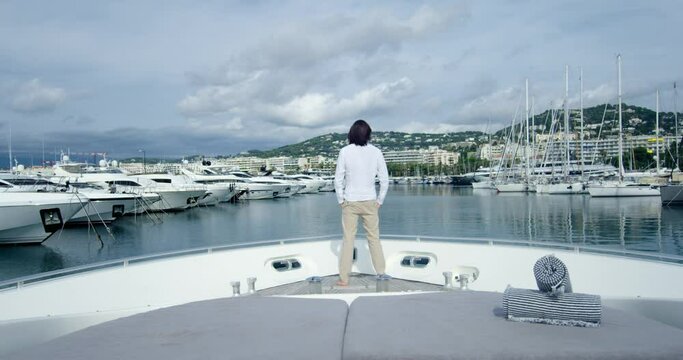Handsome man from behind standing on a boat sailing into the seagate, under the cloudy sky - Cinematic scene with RED Camera 4K