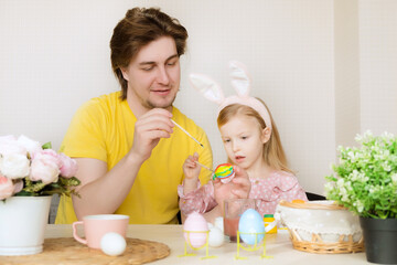 Obraz na płótnie Canvas Easter, family, holiday and children concept. Father and daughter painting eggs. Happy family preparing for Easter