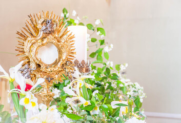 Golden monstrance with host and flowers and candles, eucharistic adoration devotion in church