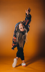 Young dancer doing acrobat moves isolated on orange wall