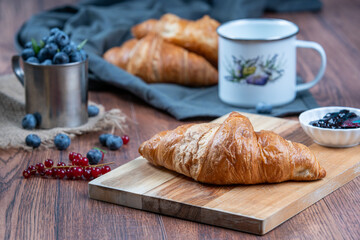 Freshly baked croissants with berries, jam on dark background, selective focus
