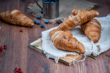 Freshly baked croissants with berries, jam on dark background, selective focus
