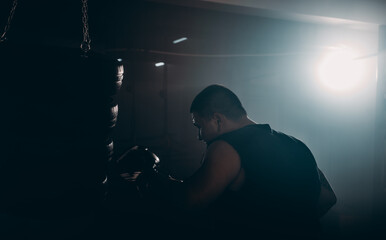 Man practicing boxing on big black bag in garage