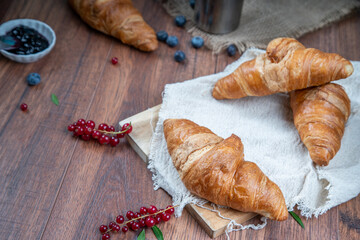 Freshly baked croissants with berries, jam on dark background, selective focus
