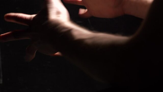 Close-up on hands of man in dark background breaking metal chains as concept of freedom and independence